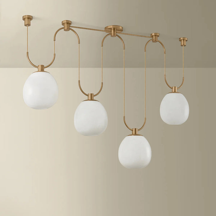 Modern ceiling light fixture with gold frame and white glass shades on a beige background