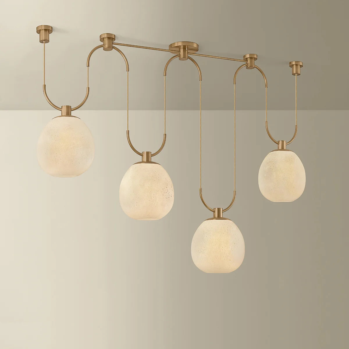 Modern ceiling light fixture with four round glass shades on a neutral background