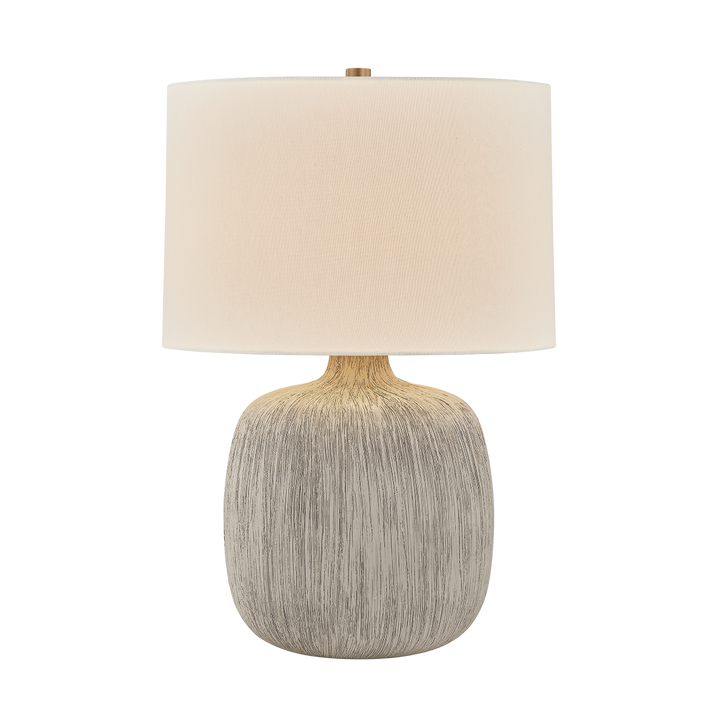 Table lamp with a textured gray base and beige fabric shade on a white background
