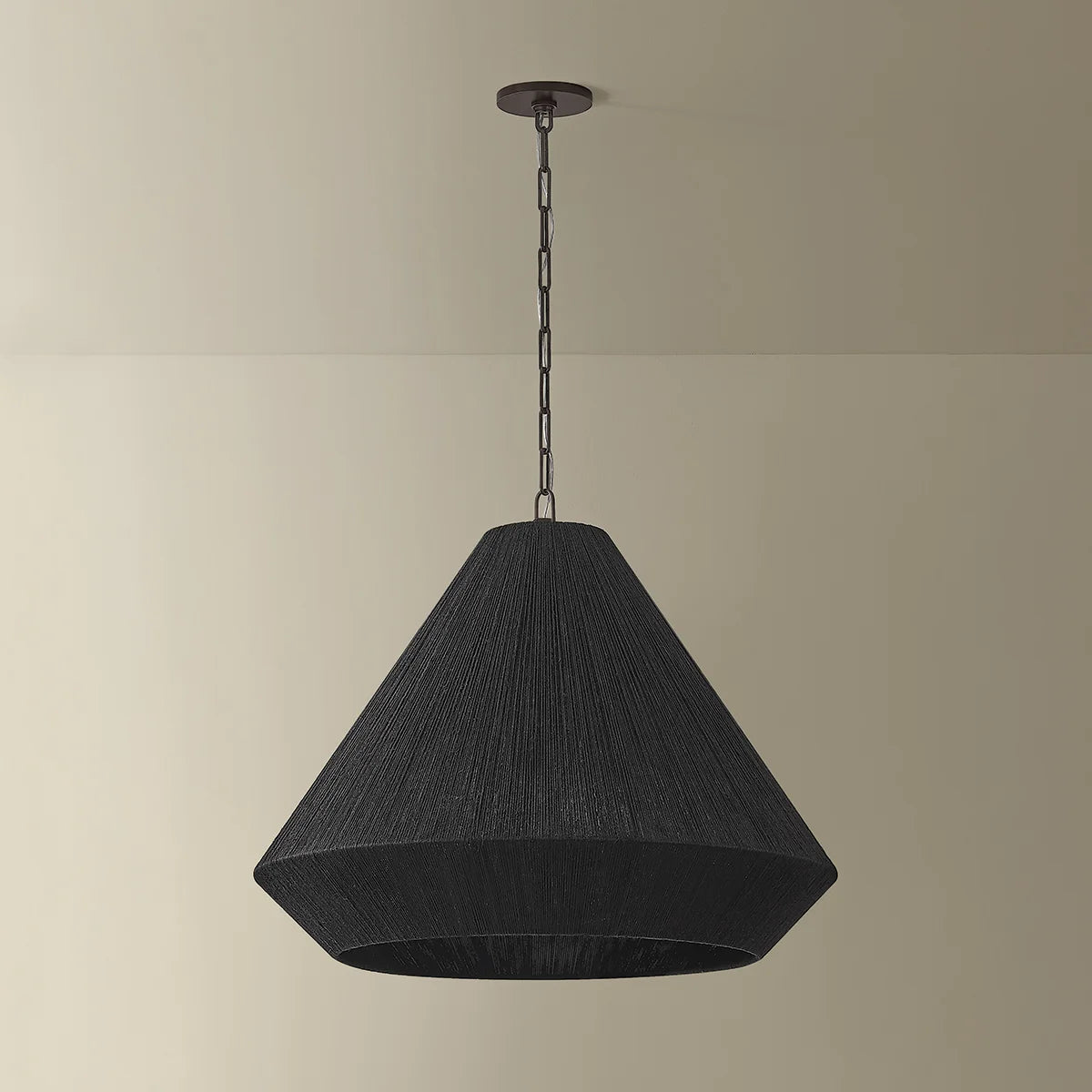 Black pendant light hanging against a beige wall