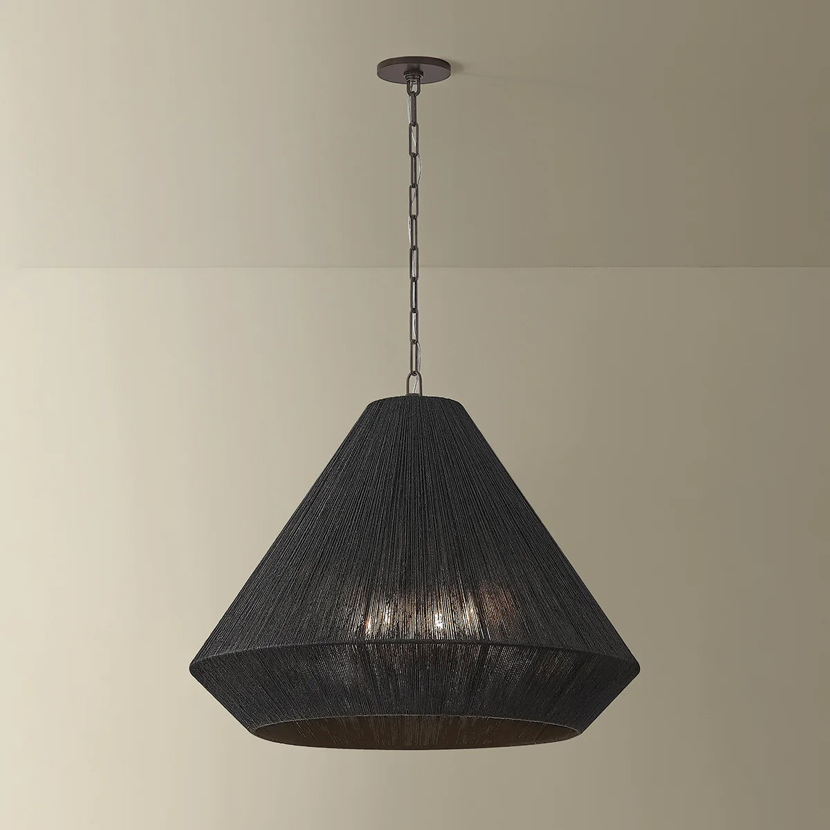 Black pendant light hanging against a beige wall