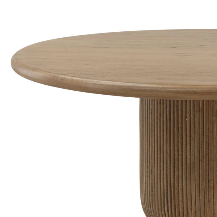Close up of round wood dining table with smooth edge and fluted pedestal base detail