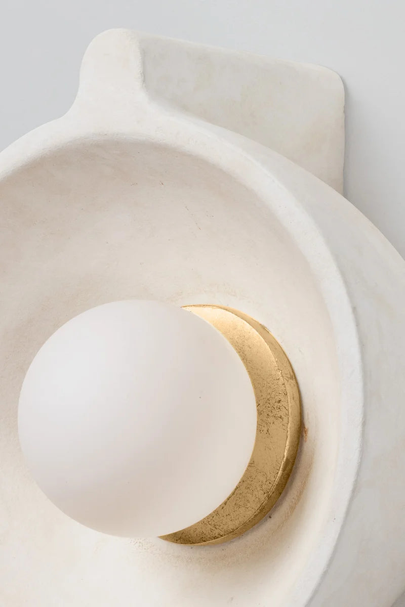 Ceramic wall sconce with a white sphere and gold accent on a light gray background