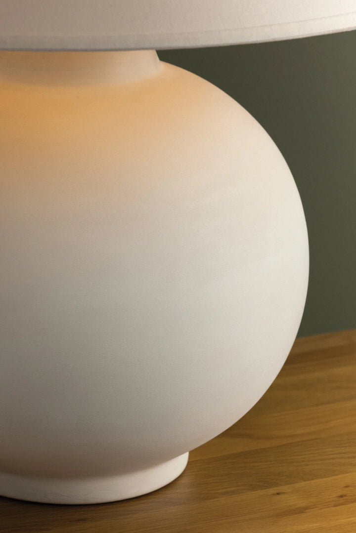 White spherical lamp on a wooden surface with a neutral background