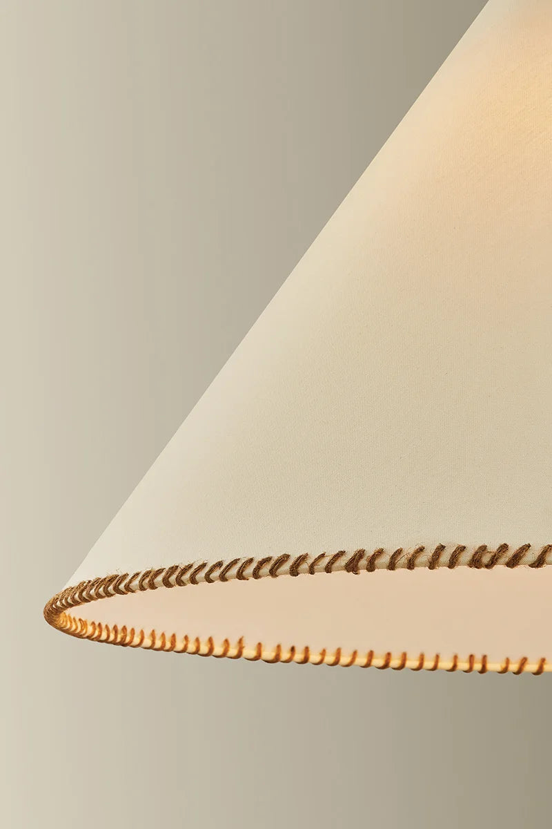 Close-up of a beige lampshade with a gold trim on a neutral background