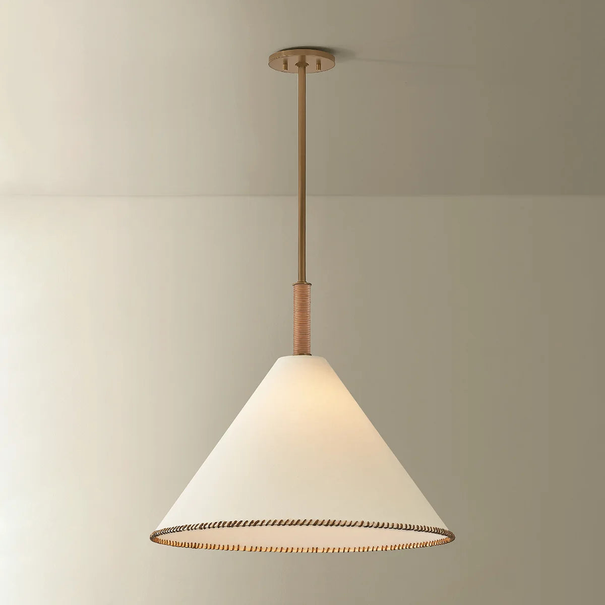 Conical pendant light with white shade and gold trim against a neutral background