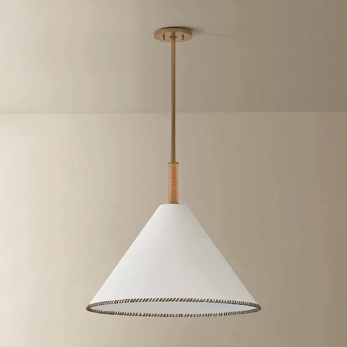 Conical pendant light with white shade and gold fixture on a beige background
