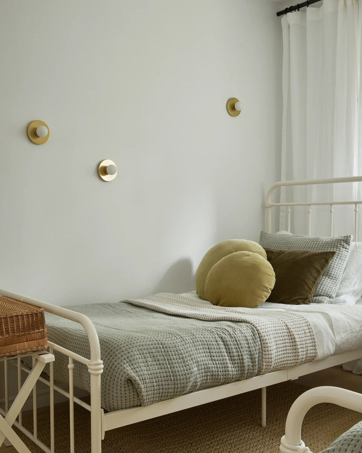 Bedroom with a white metal bed, green bedding, and decorative pillows.